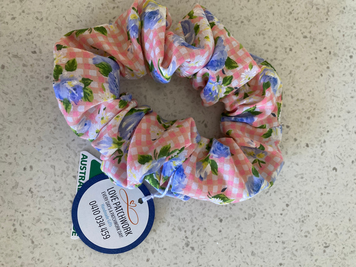 Floral patterned scrunchie with a matching tag on a textured surface