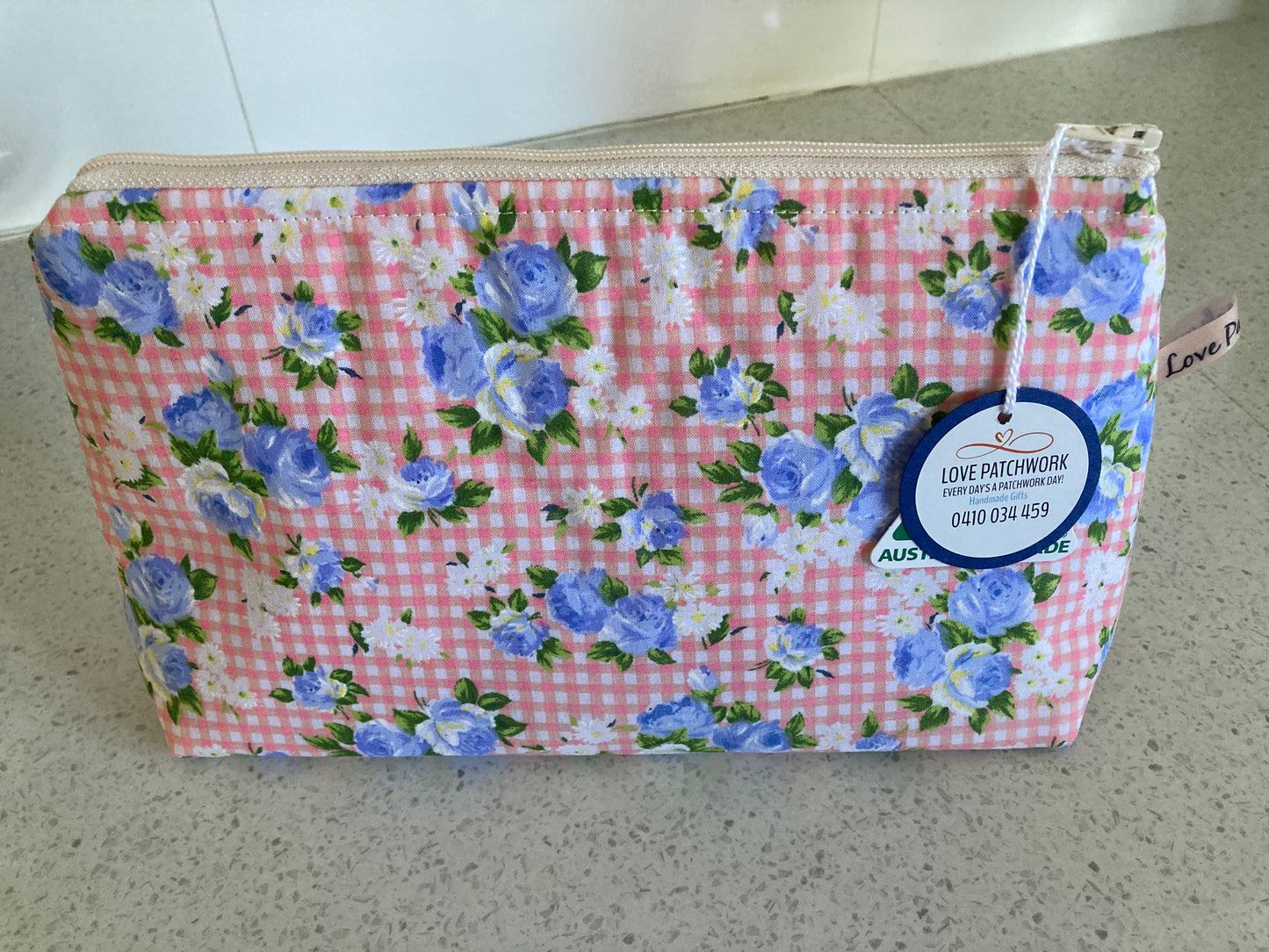 Floral patterned pouch with a visible brand tag on a neutral background