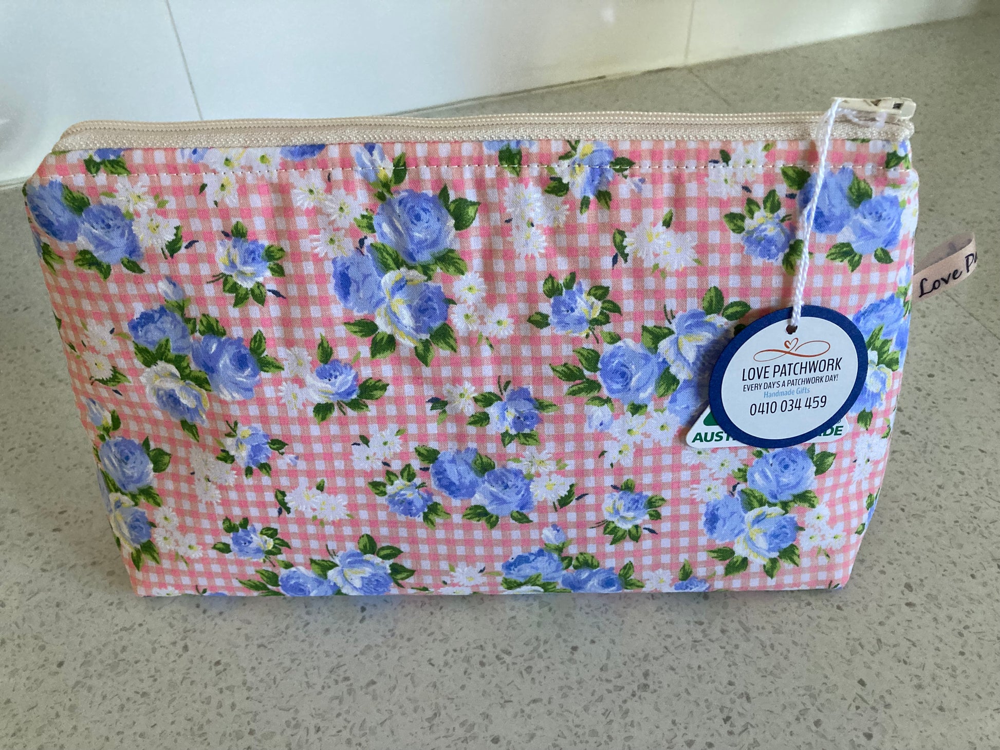 Floral patterned pouch with a visible brand tag on a neutral background