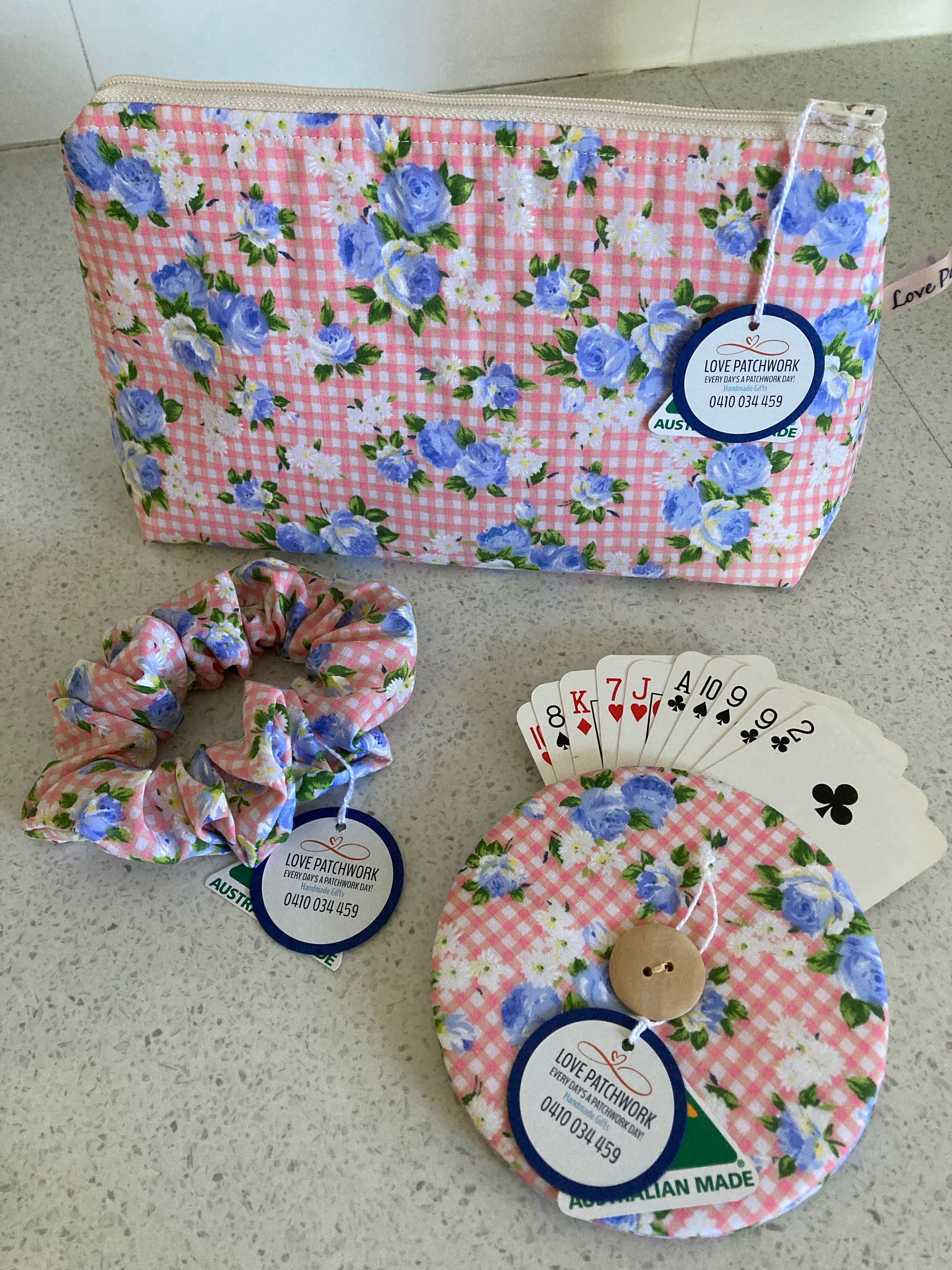 Set of floral-patterned products including a bag, card holder, and scrunchie on a neutral surface.