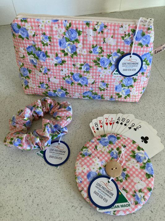 Set of floral-patterned products including a bag, card holder, and scrunchie on a neutral surface.