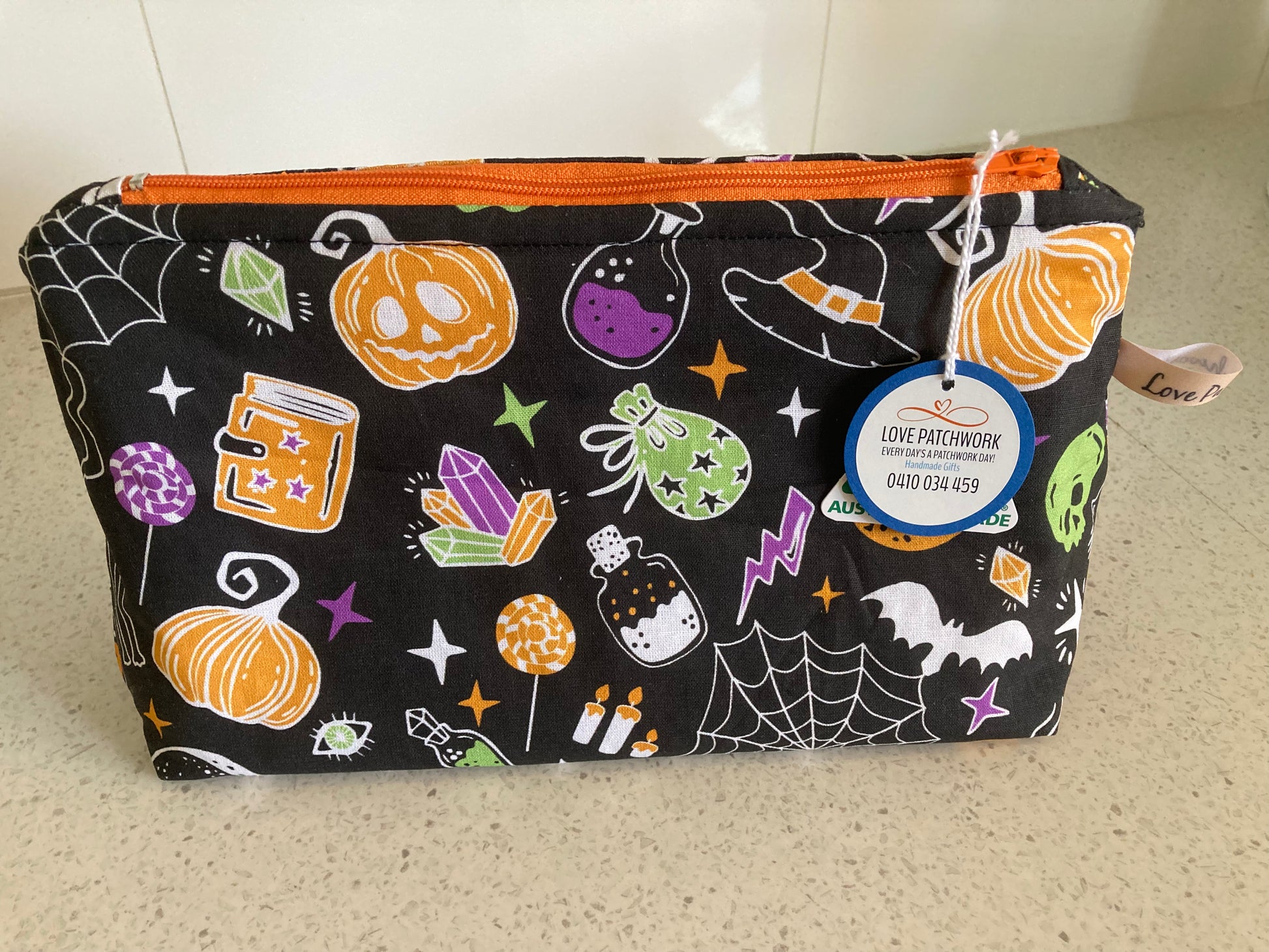 Halloween-themed pouch with pumpkins, ghosts, and other decorations on a black background. Australian Made by Love Patchwork