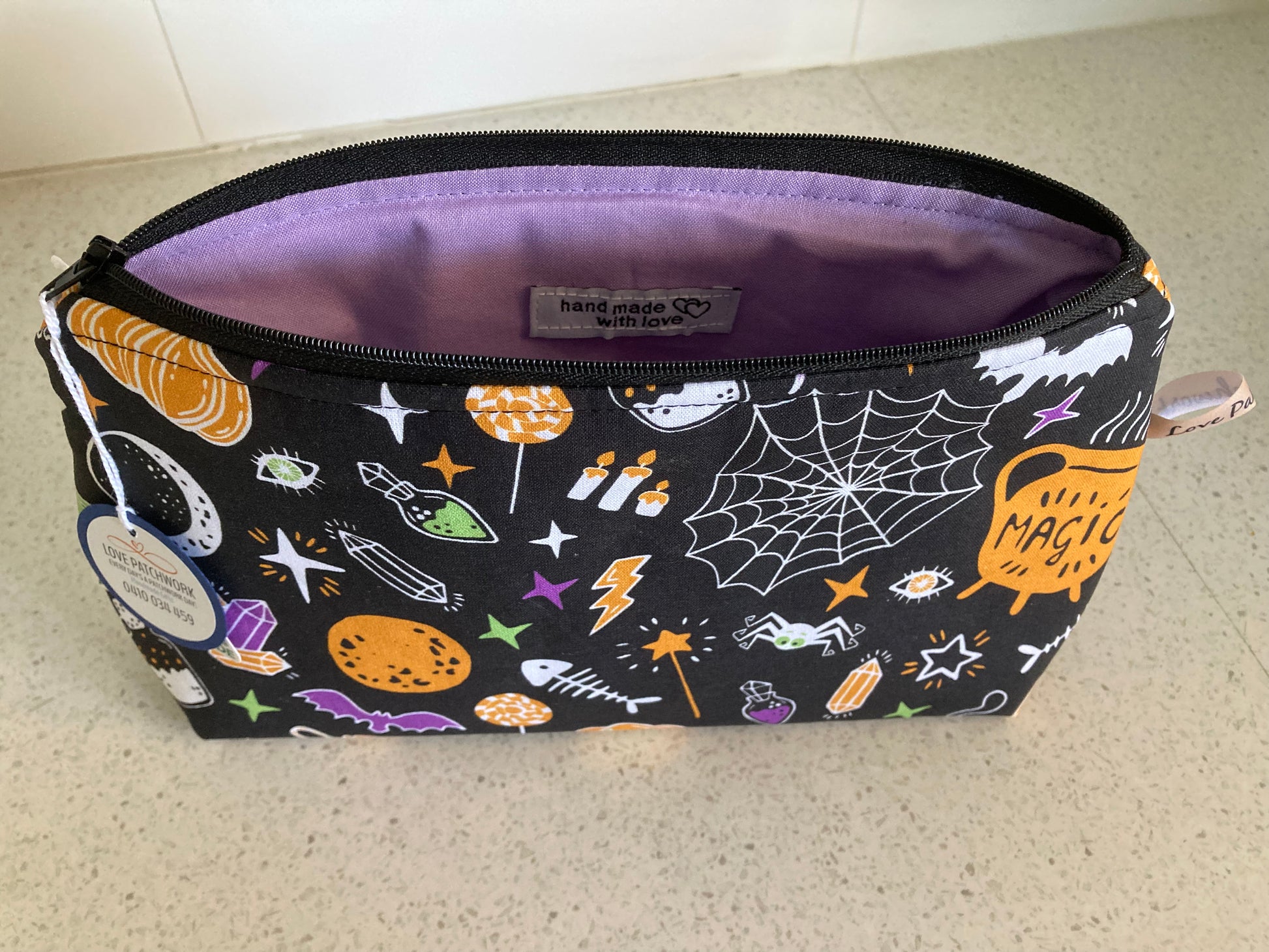 Opened zippered pouch with Halloween-themed design showing purple interior fabric with handmade with love label. Australian Made by Love Patchwork
