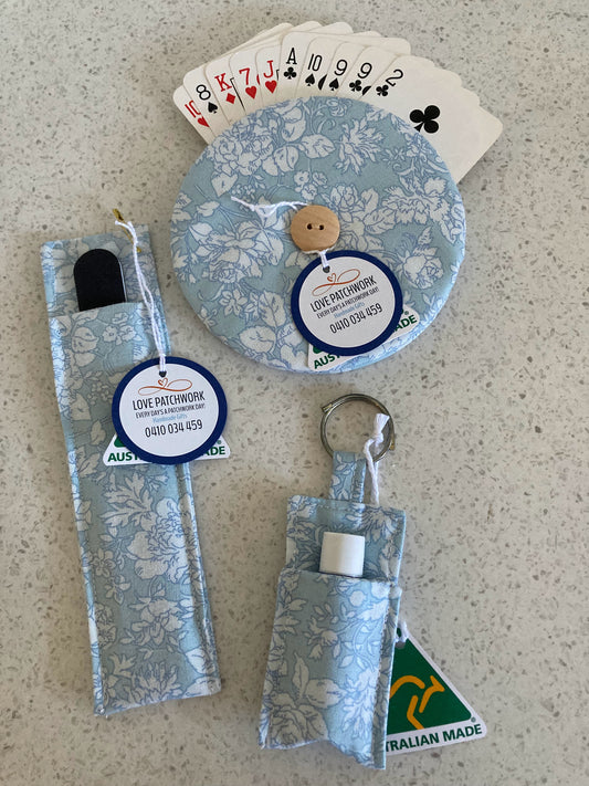 Set of playing cards with a floral design, a keychain, and a small pouch on a textured surface.