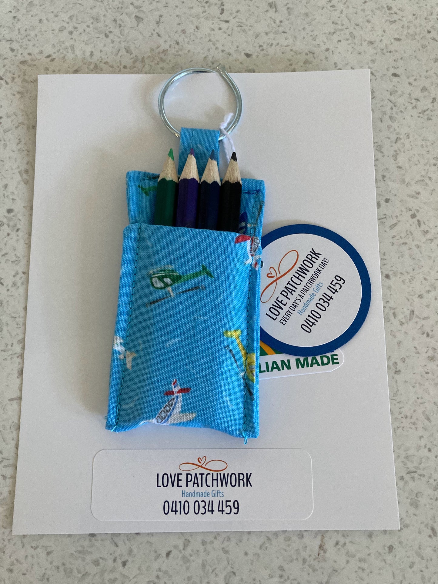 Novelty aviation keychain with colourful pencils holder on a card featuring 'Love Patchwork' branding. Australian Made